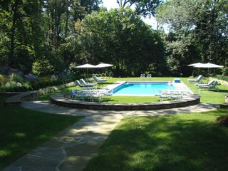 Large garden with swimming pool surrounded by grass and sun loungers