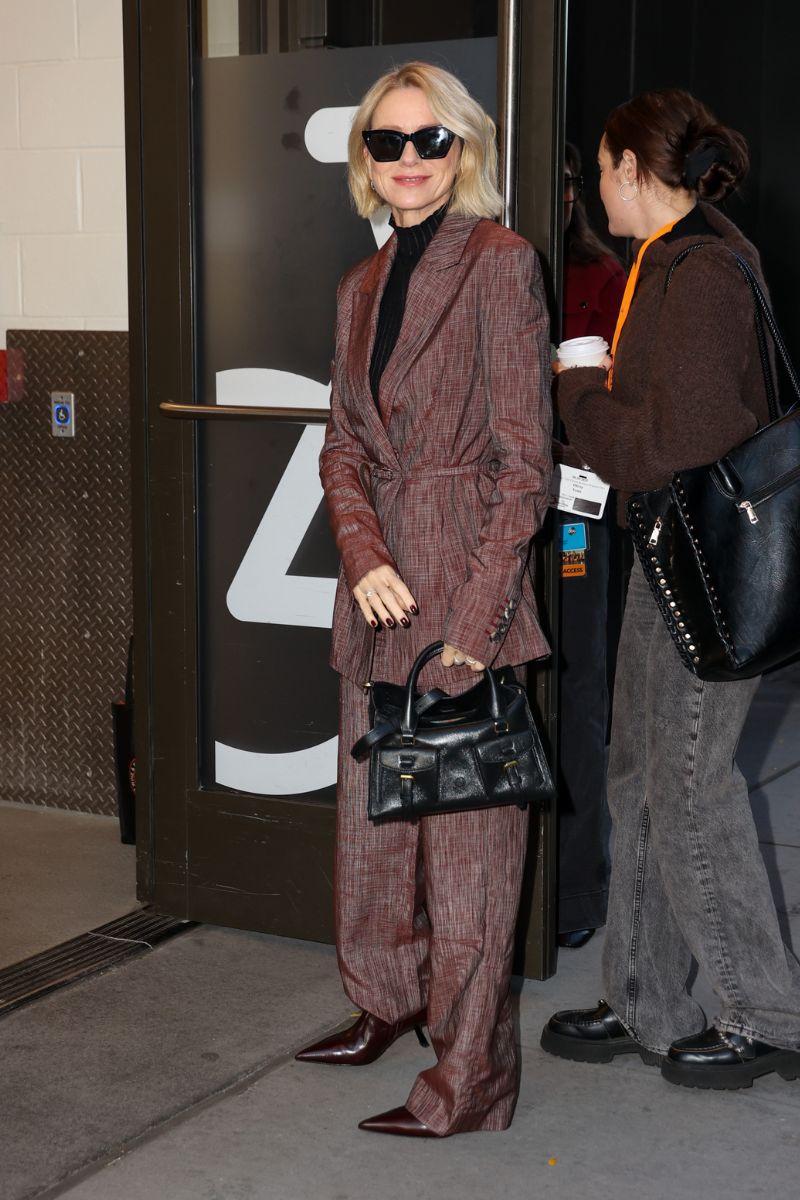 Naomi Watts in a tailored suit and black handbag