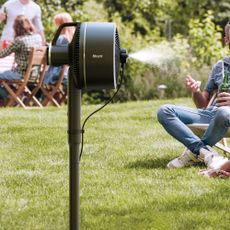Shark FlexBreeze portable fan with green grass behind and people sitting in garden