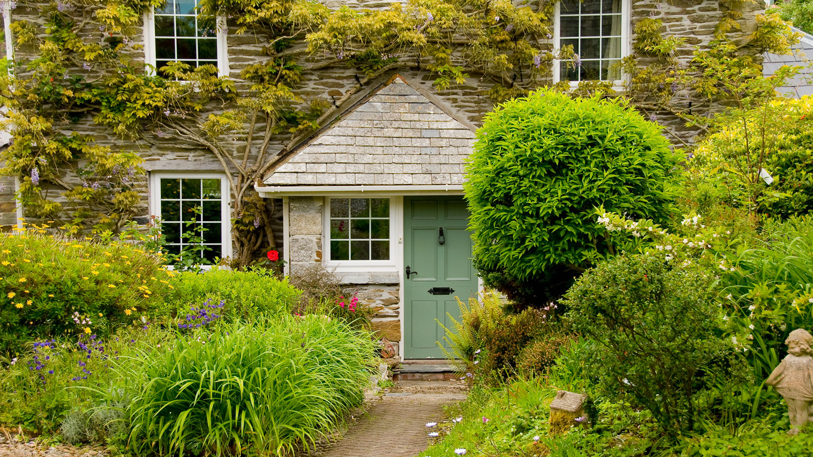stone cottage with large porch and green front door with large front garden