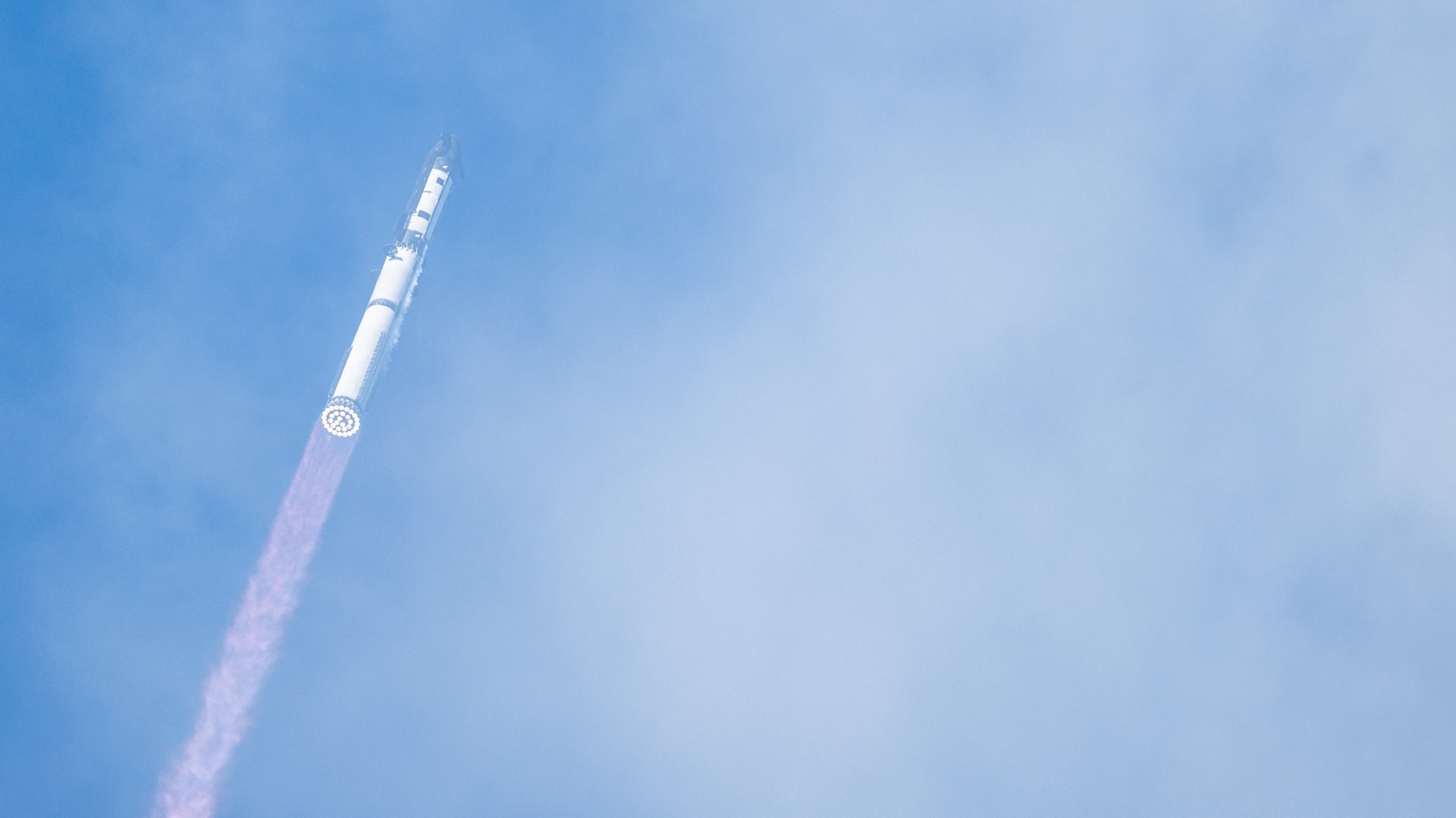 a large silver rocket launches above a plume of fire