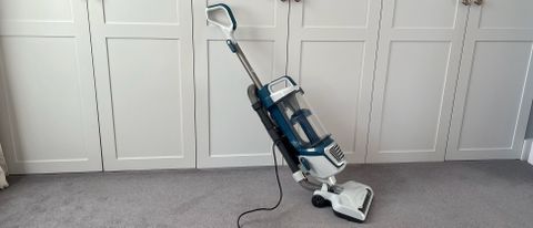 The Vacmaster Respira Pet Upright Vacuum UC0413EUK propped up against come cupbboards