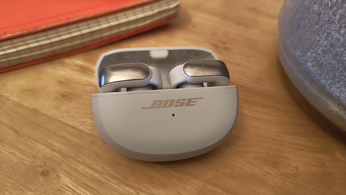 Bose Ultra Open Earbuds in their case on a wooden table