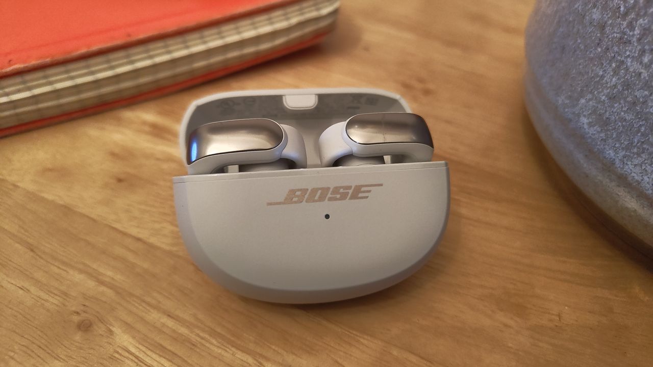 Bose Ultra Open Earbuds in their case on a wooden table