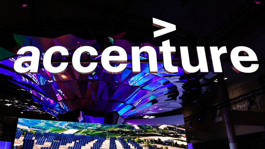 An Accenture sign displayed at a conference above an image showing rows of solar panels