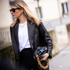 Camille Charriere, wearing white t-shirt, black pants, black leather blazer and black Bottega Veneta bag, is seen outside Mugler, during Paris Fashion Week