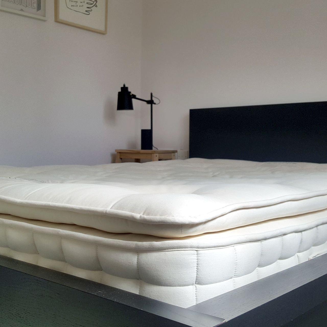 The Hypnos Select Pillow Top mattress being tested in a bedroom with pale pink walls and a black bed