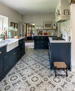 A kitchen with encaustic-style patterned kitchen floor tile ideas and blue cabinets.