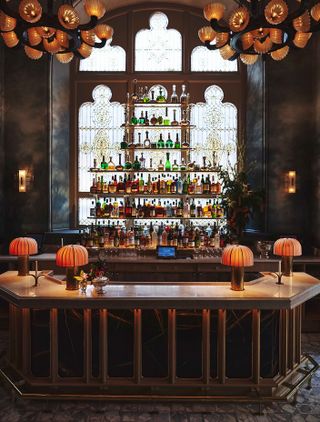 A black marble bar is surrounded by a delicately painted mural depicting a bohemian forest and is complimented by a stained glass window