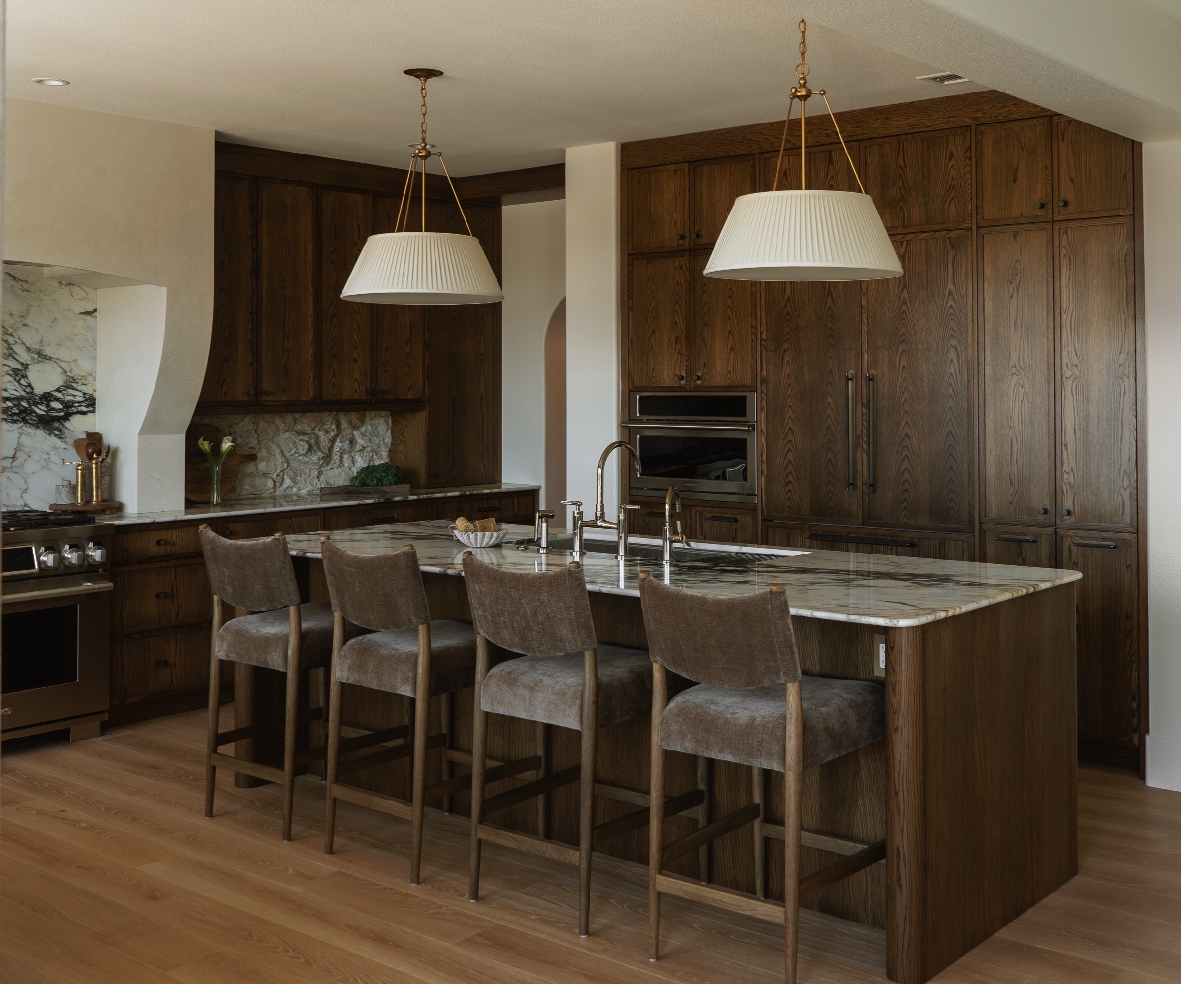 A classic kitchen with dark wood cabinets, warm white walls, and marble countertops