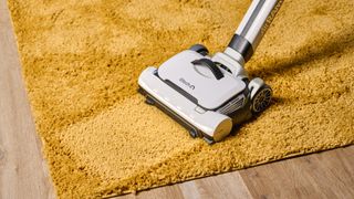 a photograph of the gtech airram 3 vacuum cleaning a thick pile yellow rug