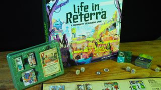 The box, tokens, components, and board of Life in Reterra laid out on a wooden table, against a black background