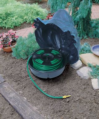 Frog shaped hose holder open to show the garden hose reel inside