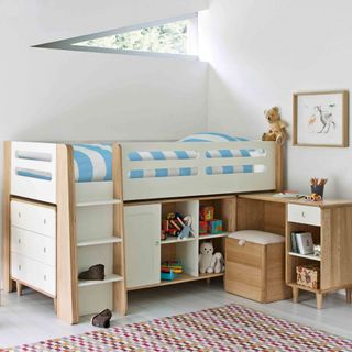 Wooden and white bunk bed with storage space on wooden floor with colorful carpet