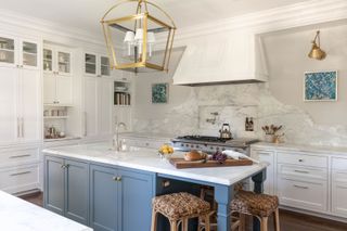 kitchen with blue island and basketweave bar stools and large brass lantern pendant light and white worktops and cabinets blue range cooker with extractor hood