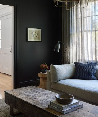 living room with black wall, wooden coffee table, neutral sofa