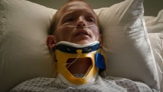 Jimmy in a neck brace laying on a hospital bed in Yellowstone.