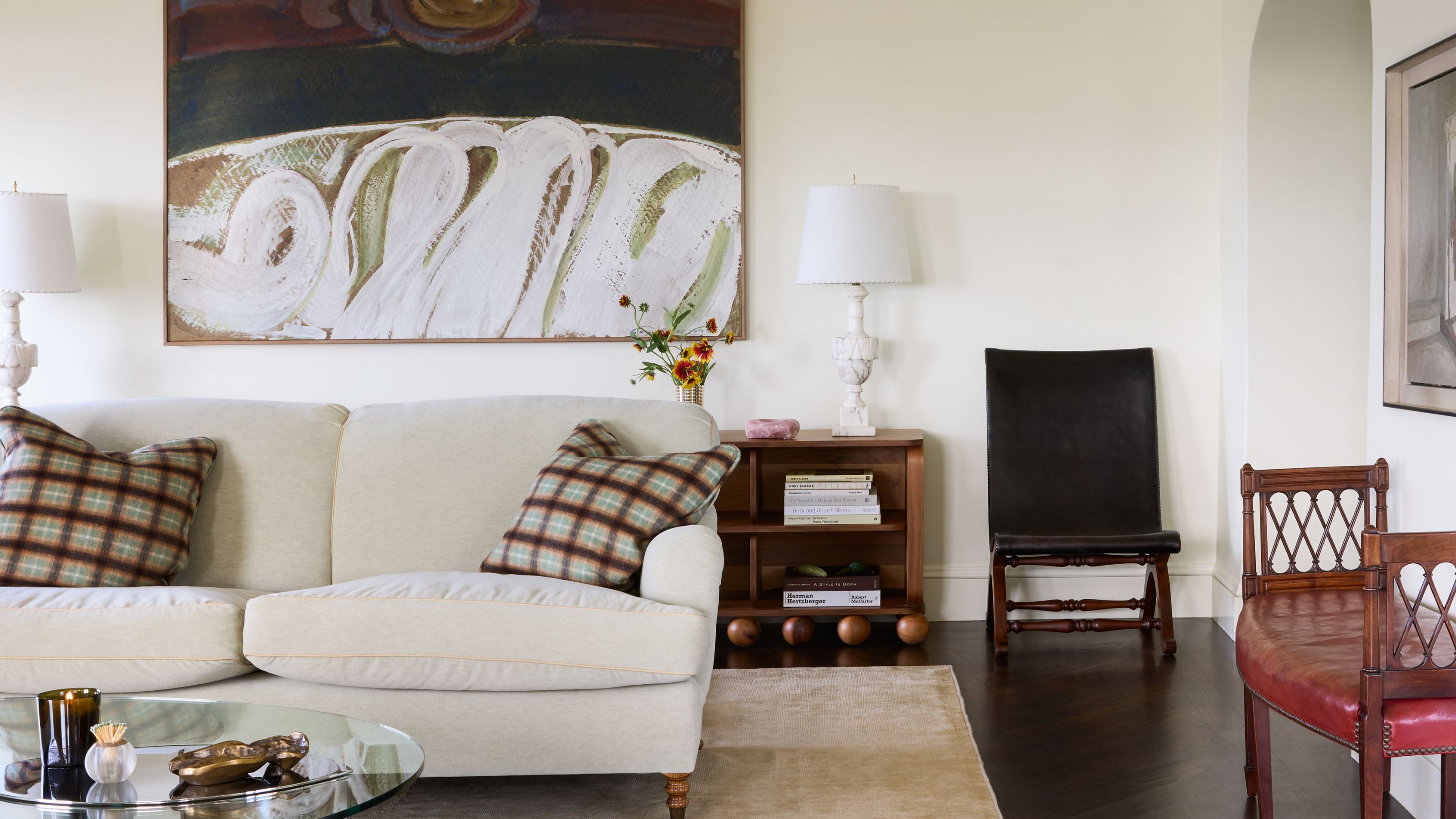 an off white living room with neutral couch, vintage furniture and large abstract wall art