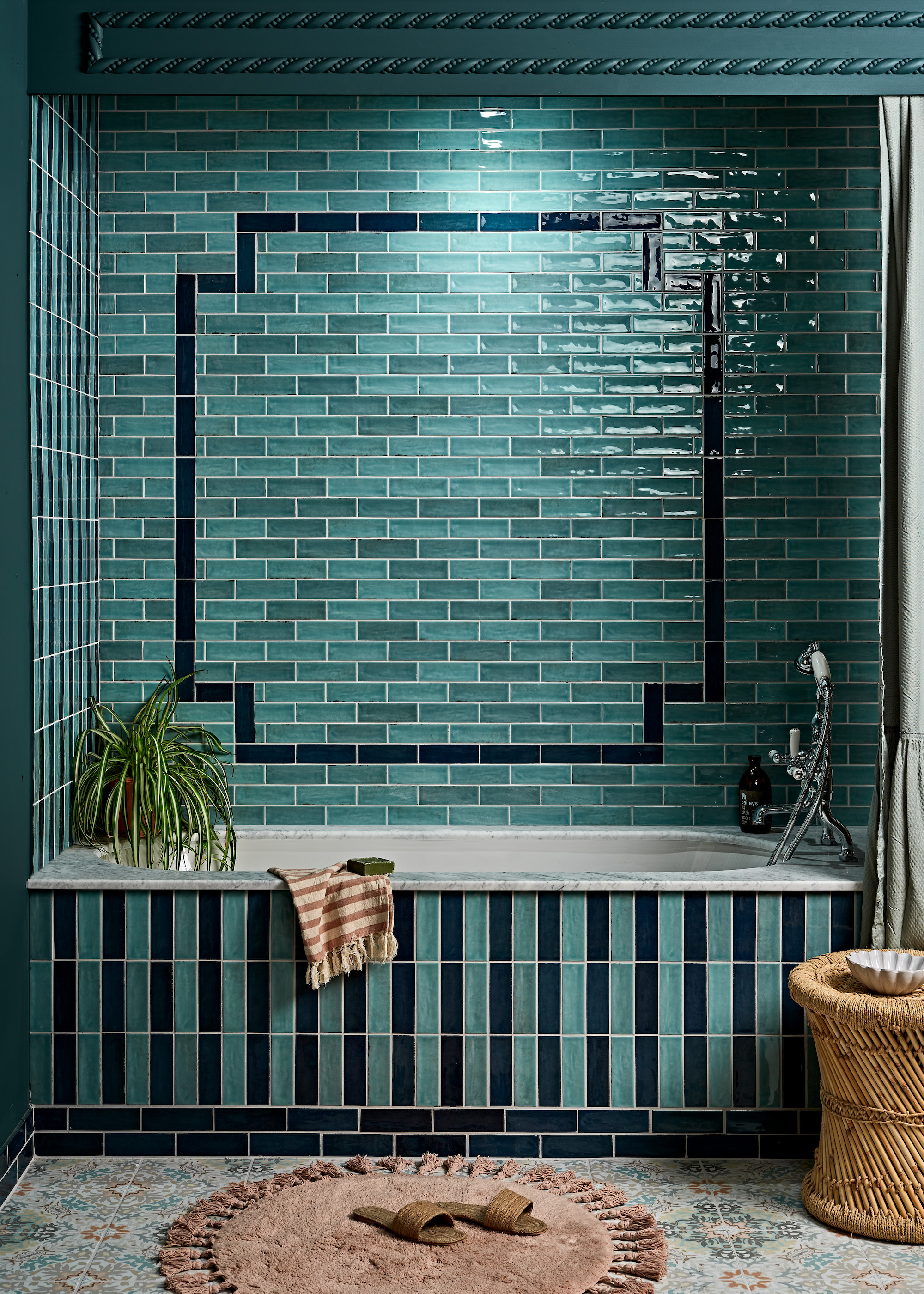 A blue bathroom with blue and black tiles arranged from the bathtub to the walls of the bathroom