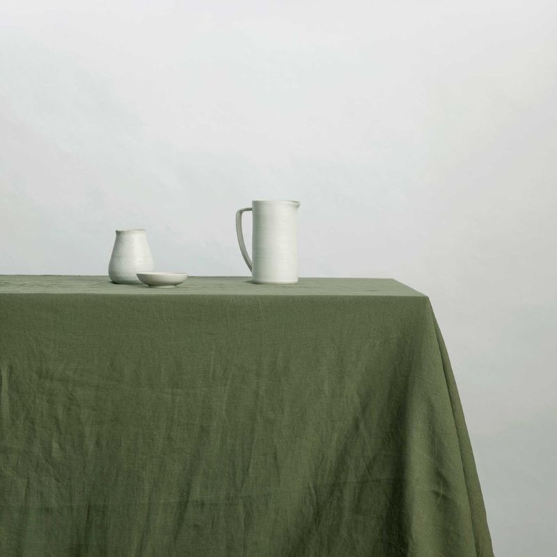 dark green tablecloth on table, small white jugs 
