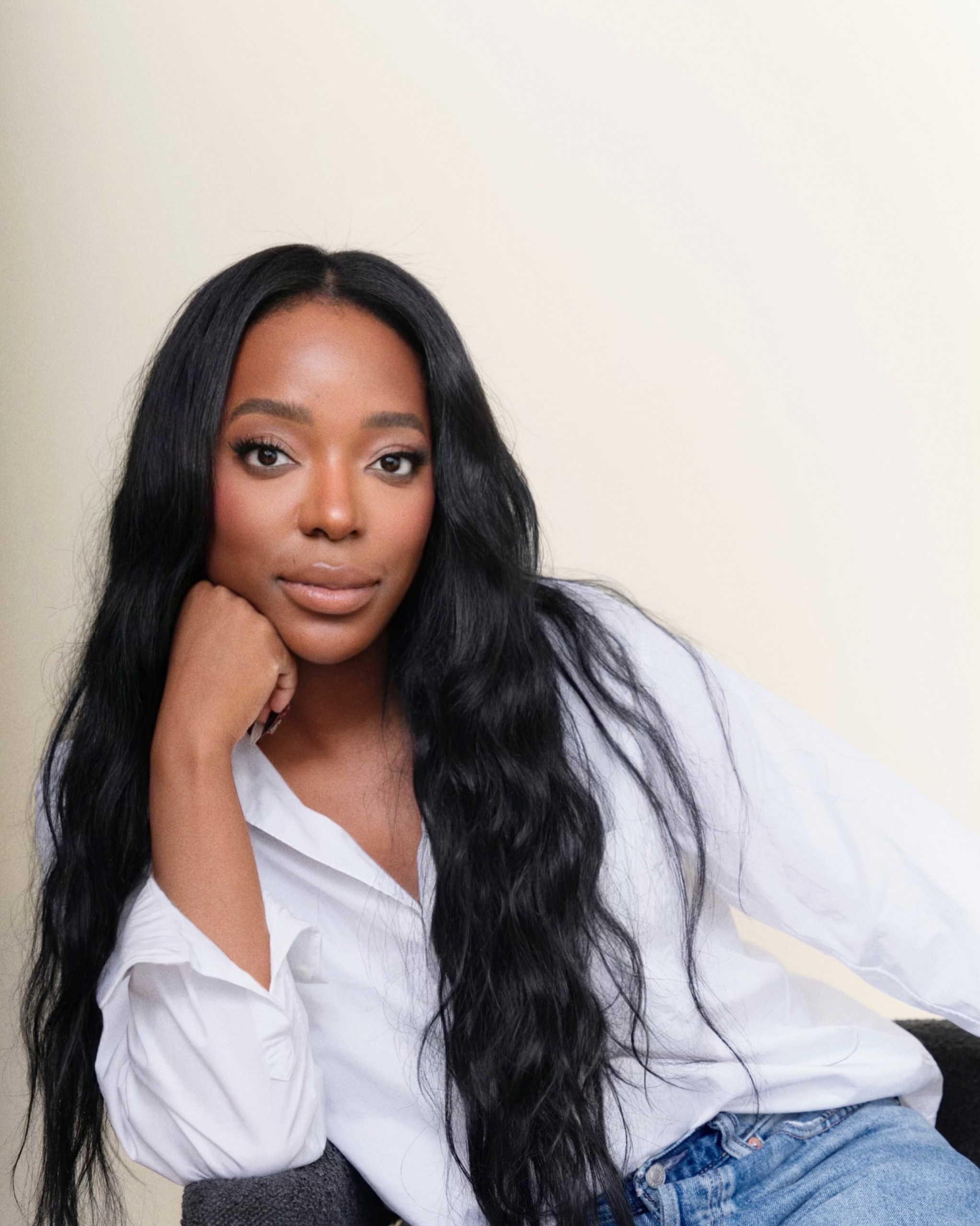 a black woman with long dark hair in a white shirt and blue jeans