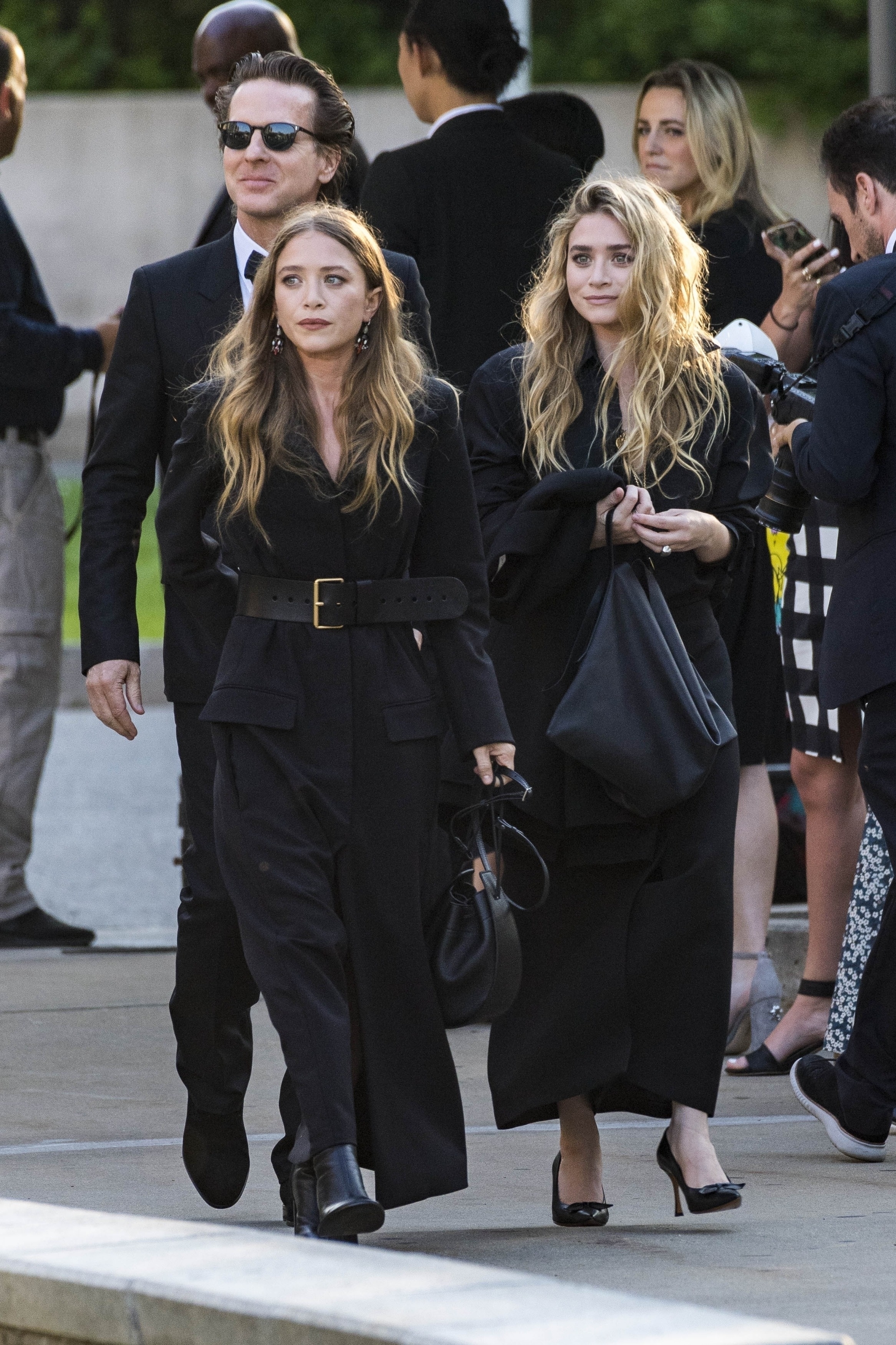 Elizabeth and Ashley Olsen walk alongside each other wearing all black.