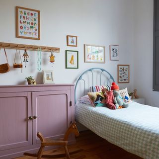 kids room with wrought iron twin bed, peg storage and painted cabinet