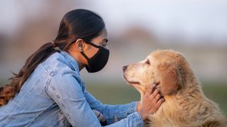 Lady in face mask with fluffy dog
