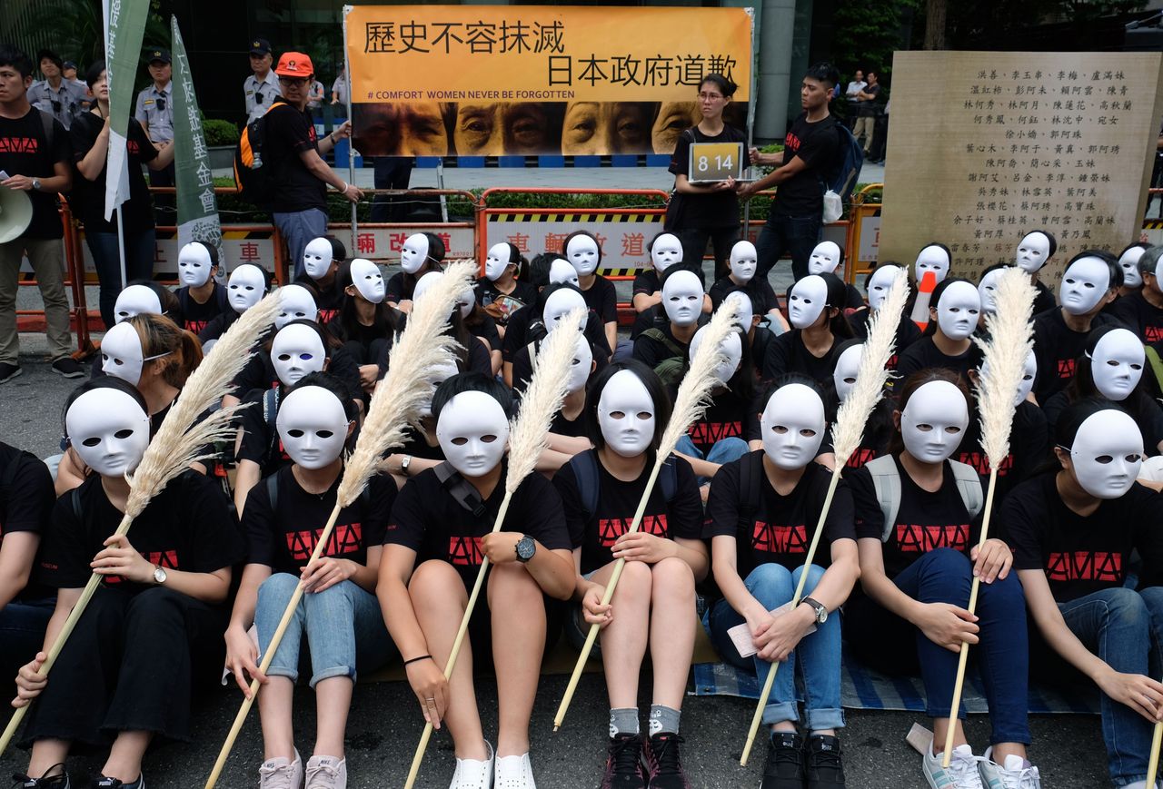 Taiwanese NGO group members wear masks during a rally to demand that the Japanese government apologise to Taiwanese &amp;quot;comfort women&amp;quot; in Taipei on August 14, 2018. - Mainstream historians agree