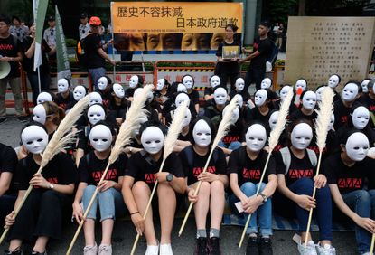 Taiwanese NGO group members wear masks during a rally to demand that the Japanese government apologise to Taiwanese "comfort women" in Taipei on August 14, 2018. - Mainstream historians agree
