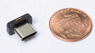 Yubico YubiKey 5C Nano ja kolikko vierekkäin harmaalla taustalla