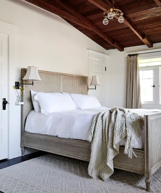 white bedroom with wooden ceiling and cane bed