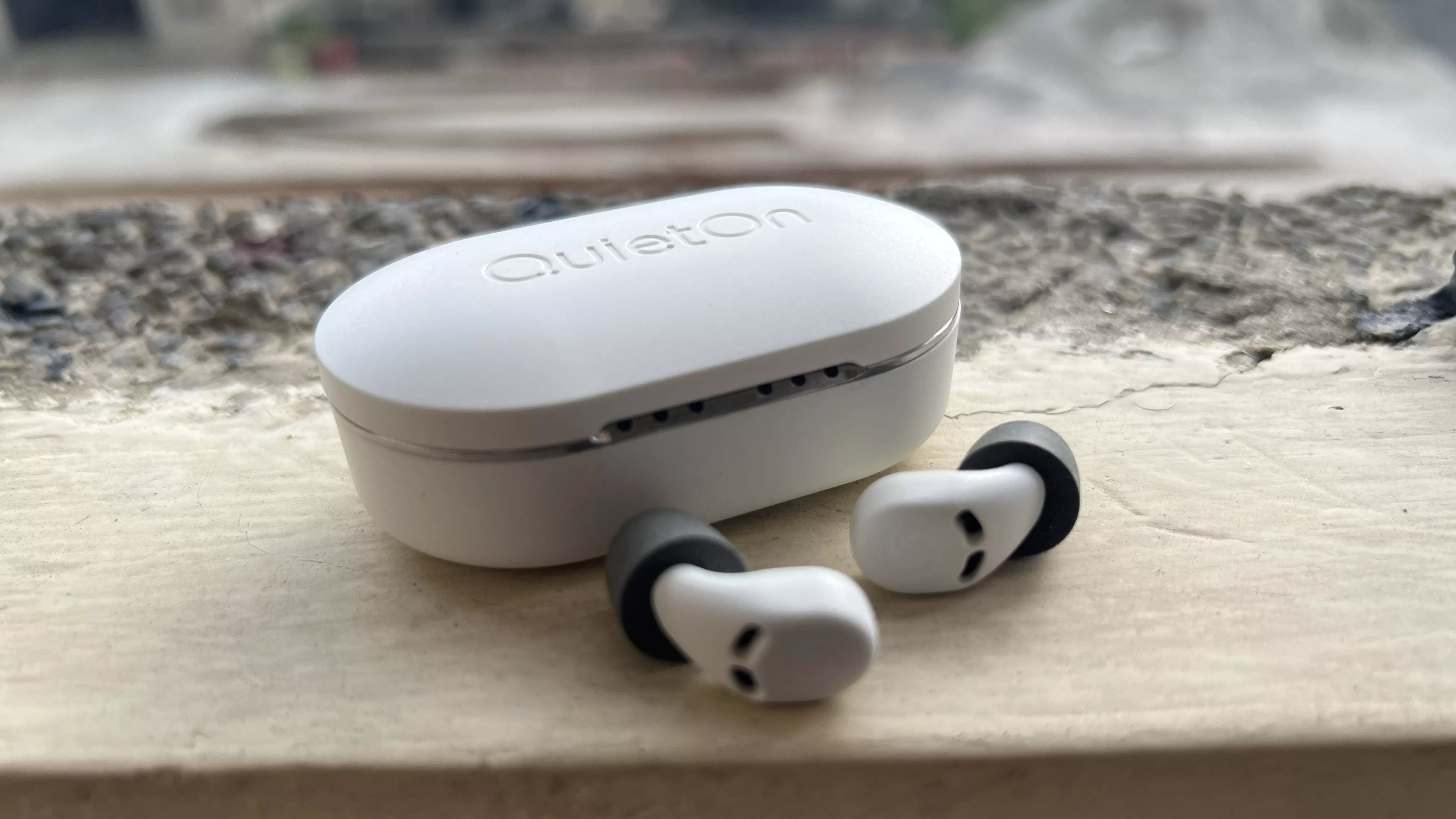 QuietOn3 earbuds outside charging case on the ground
