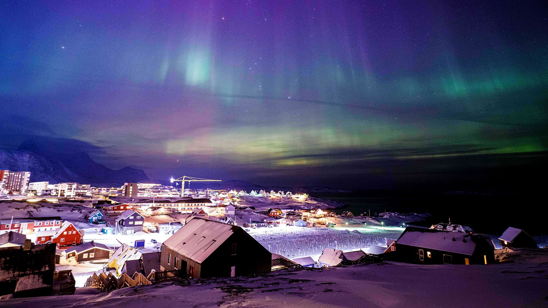 
                                The northern lights shimmer above the capital city of Nuuk, Greenland
                            