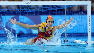 Spain&#039;s Martina Terre, leaps to save a penalty, in a red swimsuit, in the water polo at the 2024 Paris Olympic Games.