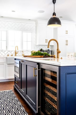 A blue shaker kitchen island with gold tap and white marble worktop