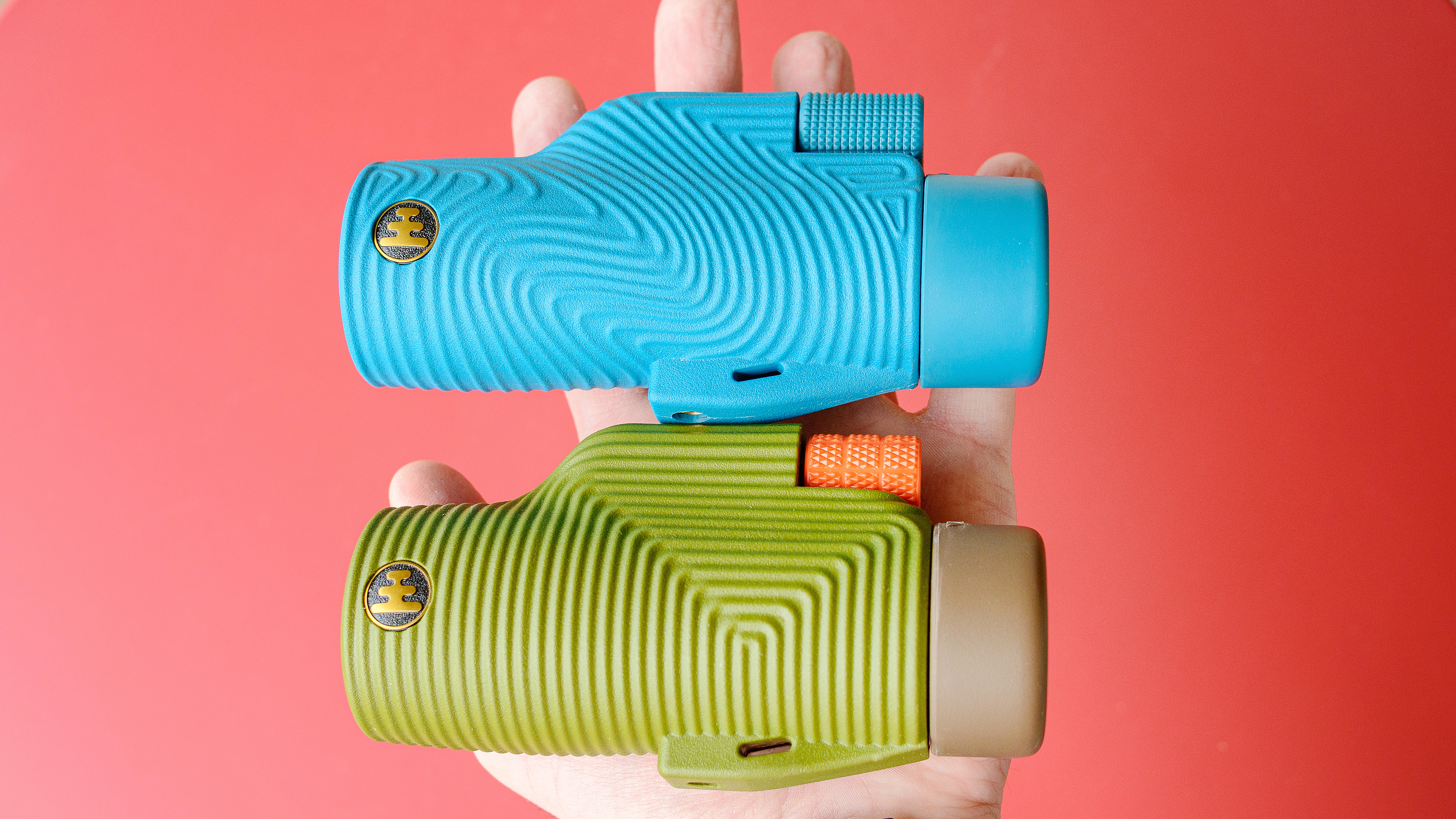 Nocs Field Tube monocular in blue.  Shown in hand next to its predecessor, the Nocs Zoom Tube, which looks the same except it is dark green and orange.