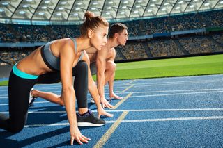 Young sporty woman and man are ready to run on racetrack.