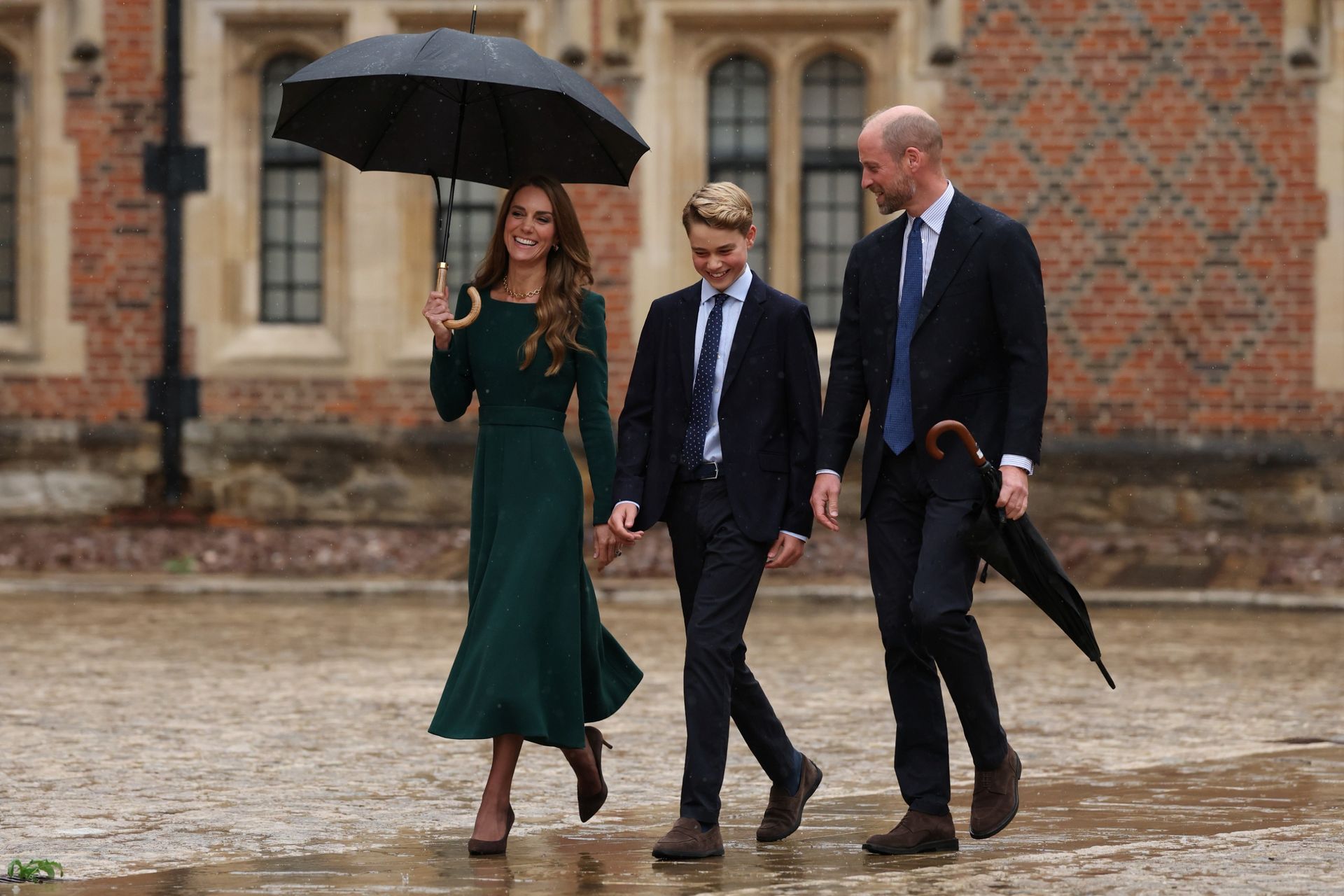 Princess Kate holding an umbrella, walking with Prince George and Prince William at Eton College
