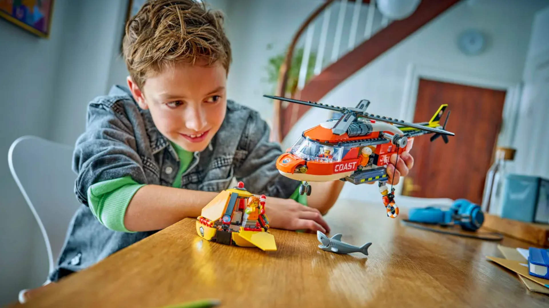 A child plays with the Lego Coast Guard set on a wooden table
