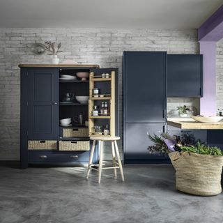 kitchen with grey concrete flooring, dark grey cabinets and a wooden ladder shelf