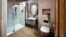 A bathroom with a large glass-fronted shower and floating vanity and toilet with alcove shelving