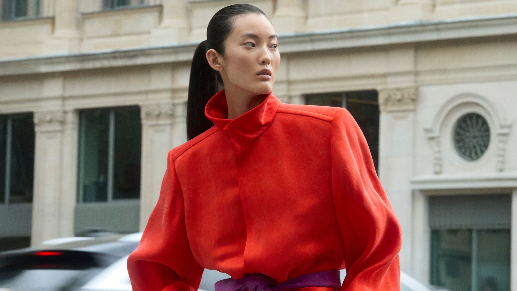 a model posing in paris wearing a red coat
