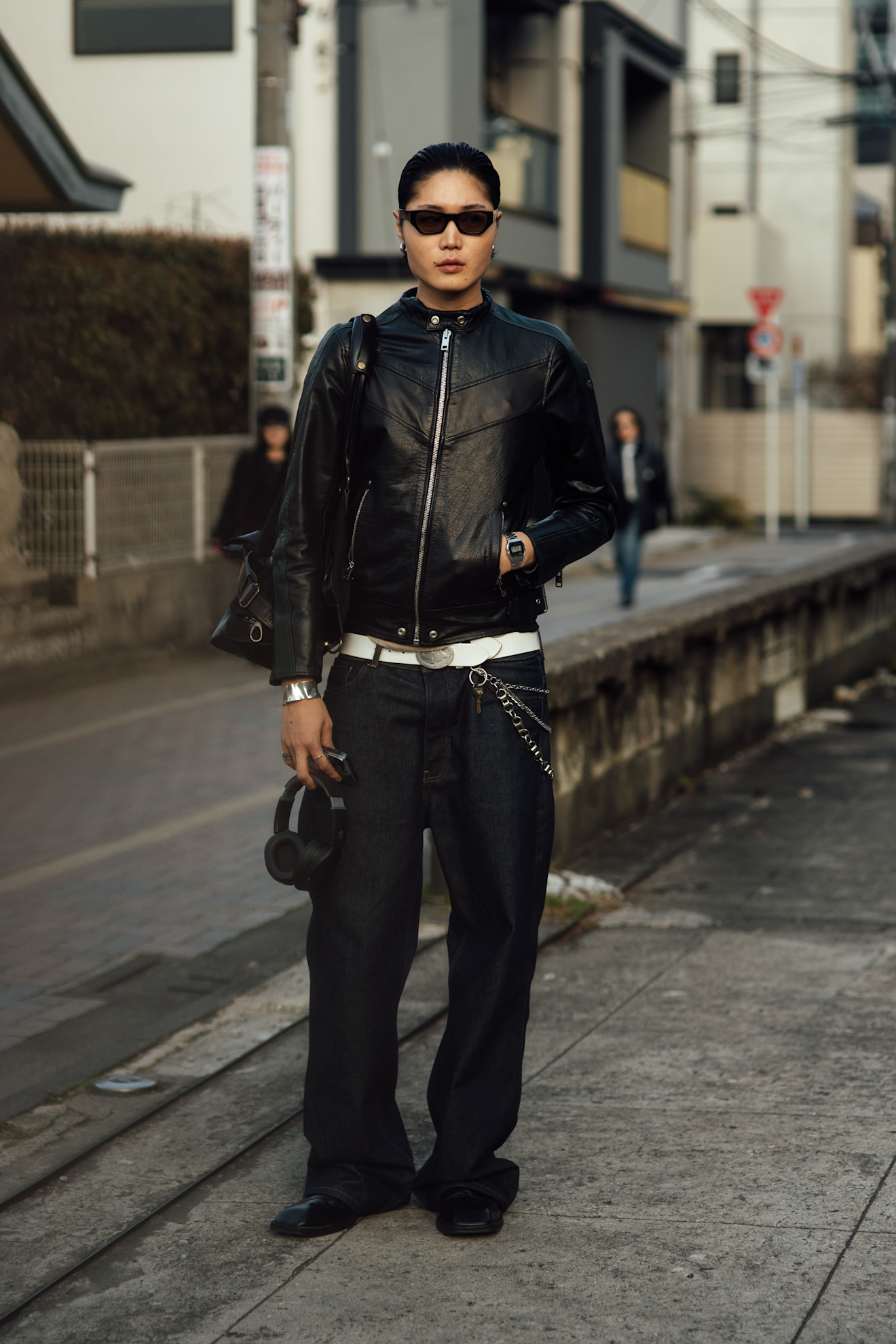 woman wearing a black leather jacket and black trousrs with a white belt in Tokyo.