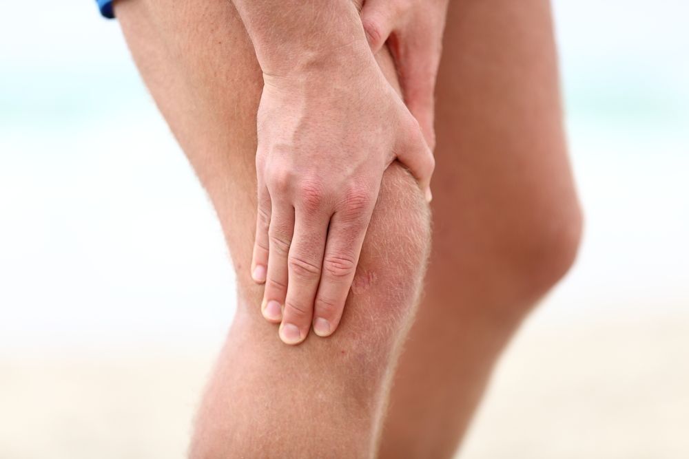 A runner clutches his knee in pain.