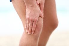 A runner clutches his knee in pain.