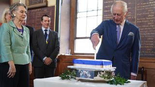 King Charles III cuts a cake, during a visit to the Grade I listed North Wing of St Bartholomew's Hospital