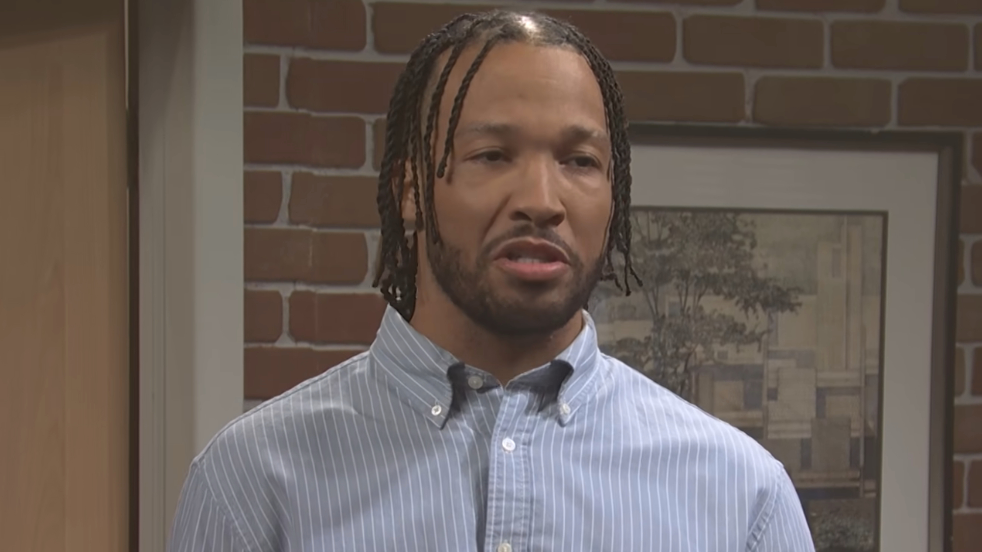 Jalen Brunson wears a button up shirt during an office sketch on SNL.
