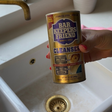 Hand holding a pot of Barkeepers Friend over a sink