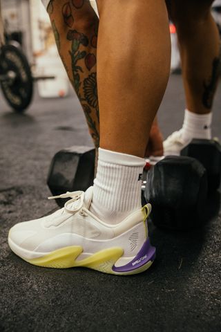 Press shot of the R.A.D One V2 shoe in action as someone picks up a dumbbell during training.